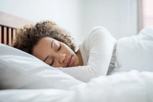 Mujer descansando plácidamente en la cama tras mejorar sus hábitos de sueño