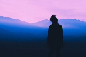 Persona contemplando el amanecer en tonos azul y violeta, símbolo de esperanza y reflexión en el Día Mundial contra la Depresión.