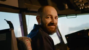 Operador ferroviario en la cabina de conducción sonriendo, representando la fase de acumulación silenciosa previa a una baja laboral por estrés en el sector transporte